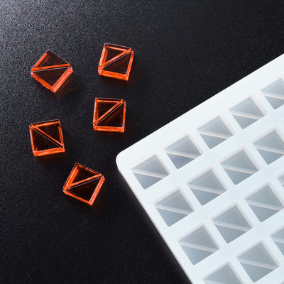 Orange geometric silicone molds on a black surface with a white silicone mold in the foreground.