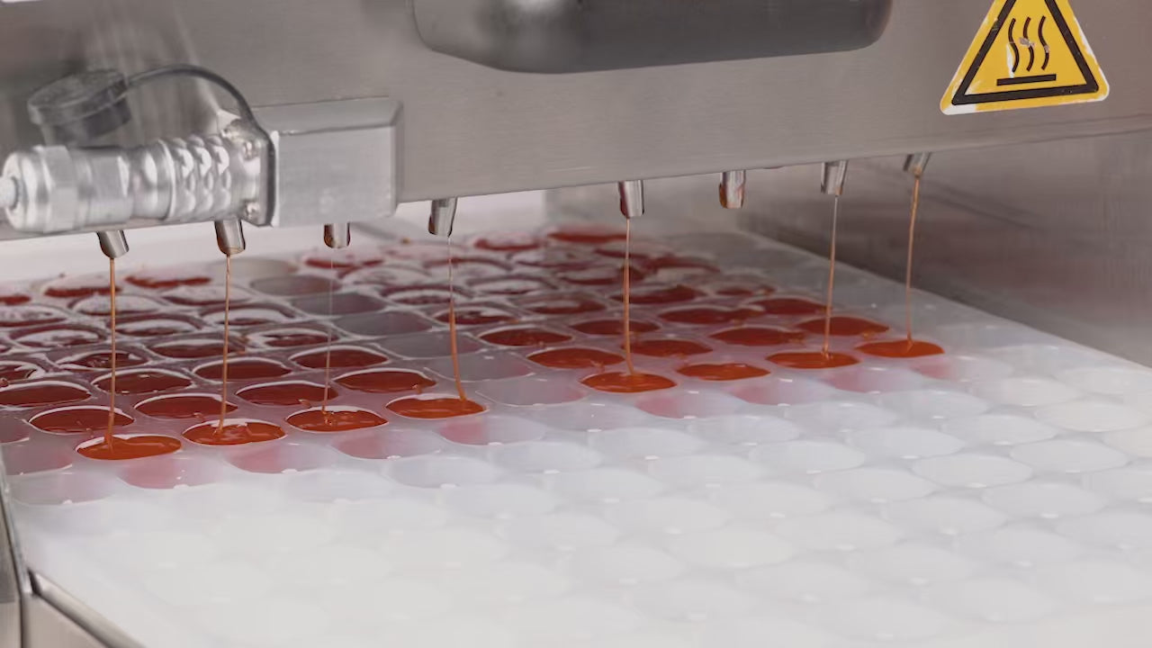 Load video: confectioners at work pouring gummies from a universal depositor into molds by bold maker