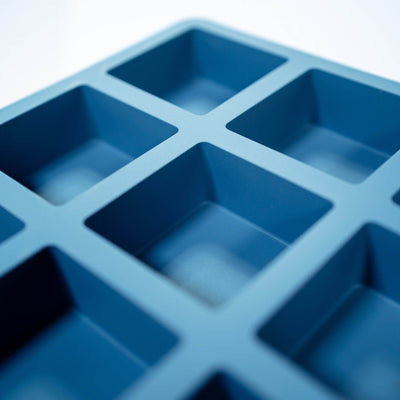 CloseupCornerofMold63mL2InchSquareInjectionMoldedPlain15CavityBrowniePanMoldBluewithWhiteBackground