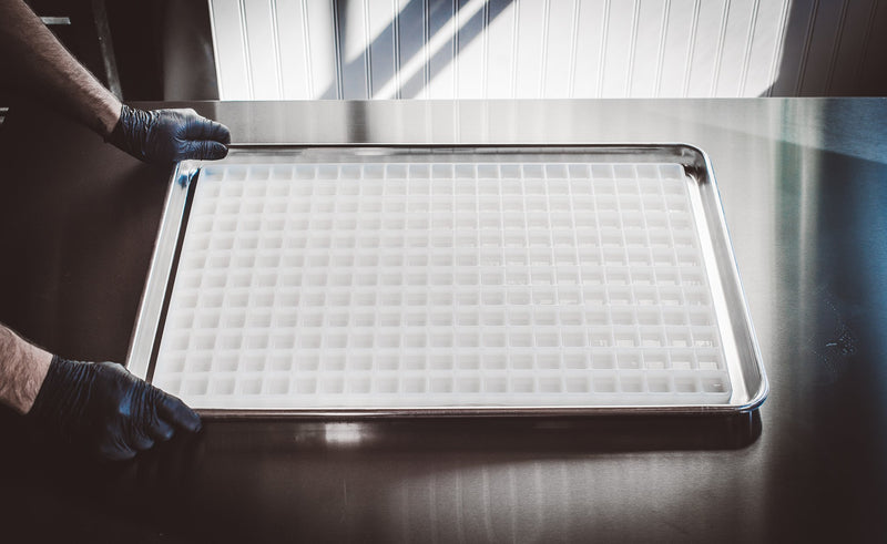 HandsHoldingBakingTrayonKitchenTable6.8mLBarCandyMoldPlain252Cavities100PercentPlatinumSiliconeFullSheet